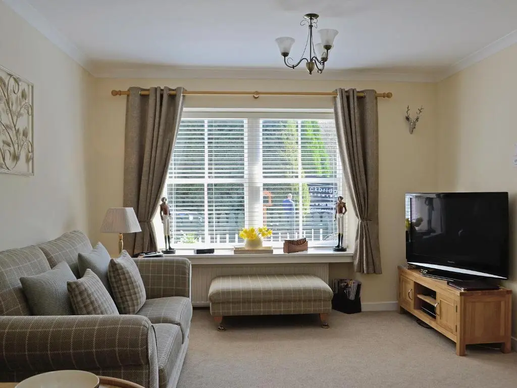 a living room with a couch and a large window at Song Bird Cottage in Lochend