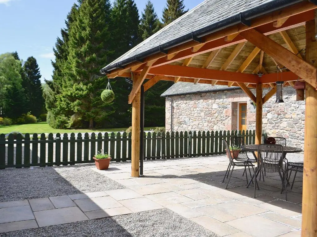 a wooden pavilion with a table and chairs on a patio at Ladybird Cottage in Lochend