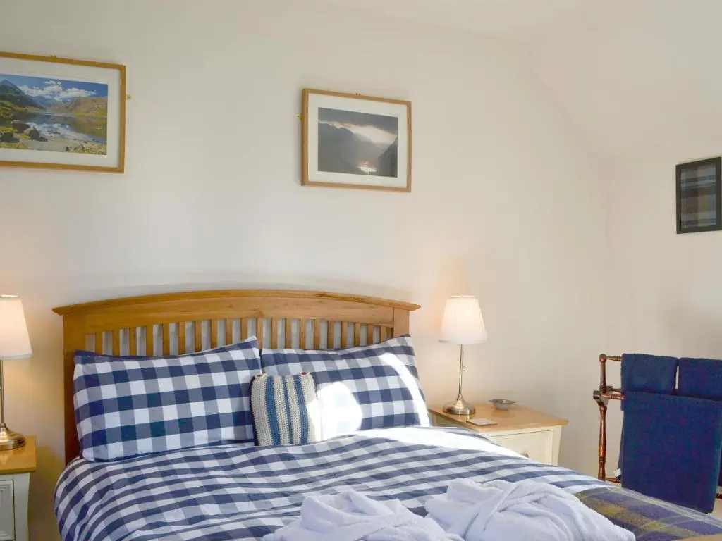 a bedroom with a bed with blue and white pillows at Langside in Kingussie