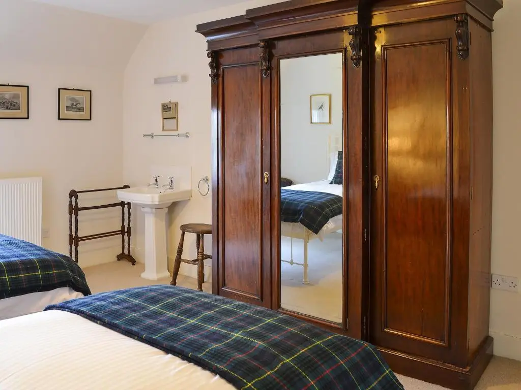 a bedroom with two beds and a cabinet with a mirror at Einich in Newtonmore
