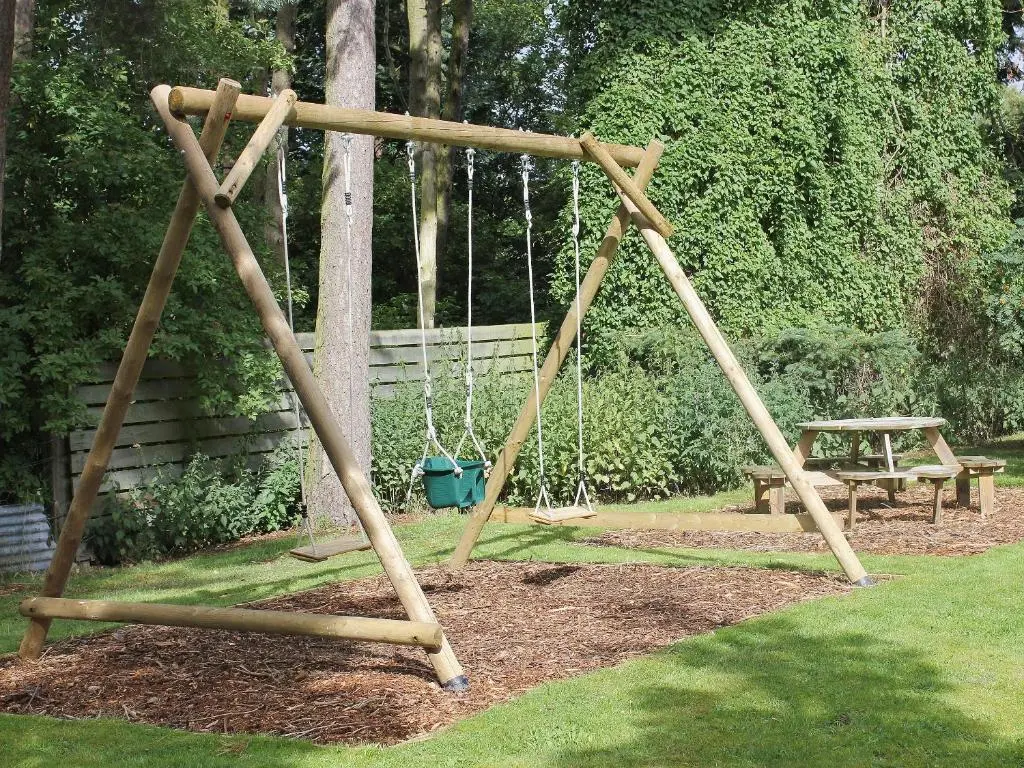 a swing set in a park with a picnic table at Einich in Newtonmore