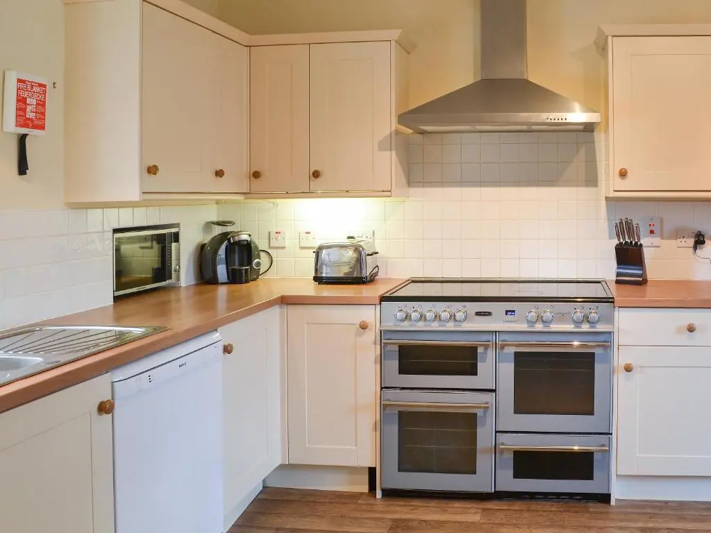 a kitchen with white cabinets and a stove top oven at Einich in Newtonmore