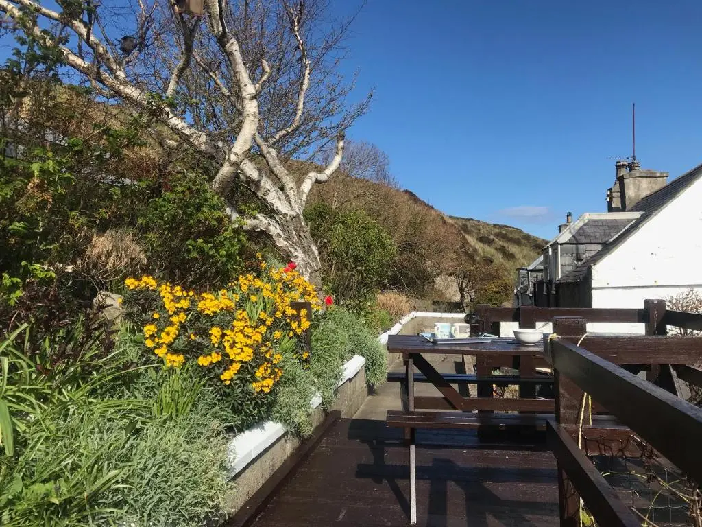 a table and benches on a patio with flowers at Boatmans Cottage - 27787 in Portessie