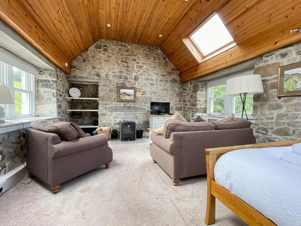 a bedroom with two couches and a stone wall at Glacour Studio Cottage in Bridgend