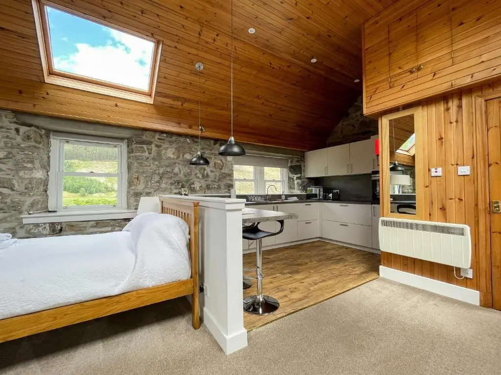 a small bedroom with a bed and a kitchen at Glacour Studio Cottage in Bridgend