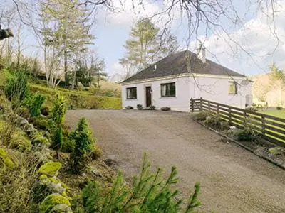 a small white house with a fence and a road at Holly Cottage in Gorstan