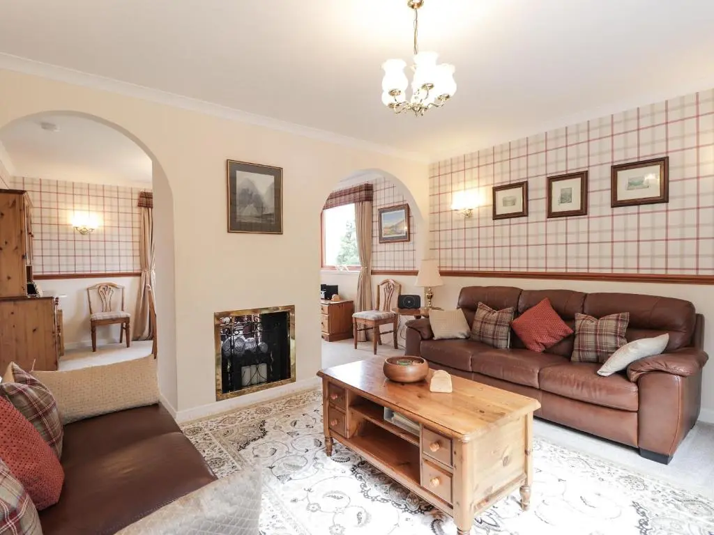 a living room with a couch and a table at Holly Cottage in Gorstan