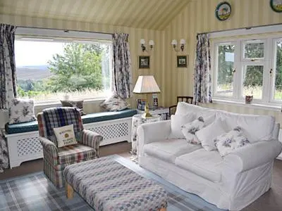 a living room with a white couch and a chair at Reid's Cottage in Lairg