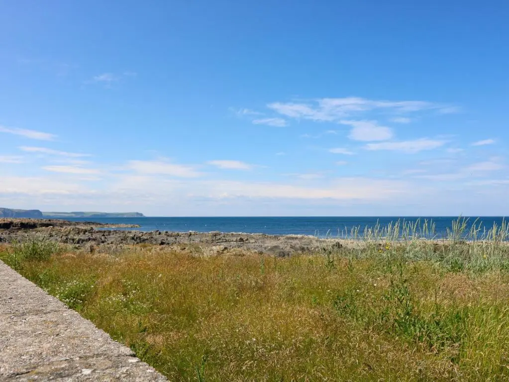 a field of grass with the ocean in the background at Shoreline House in Fraserburgh