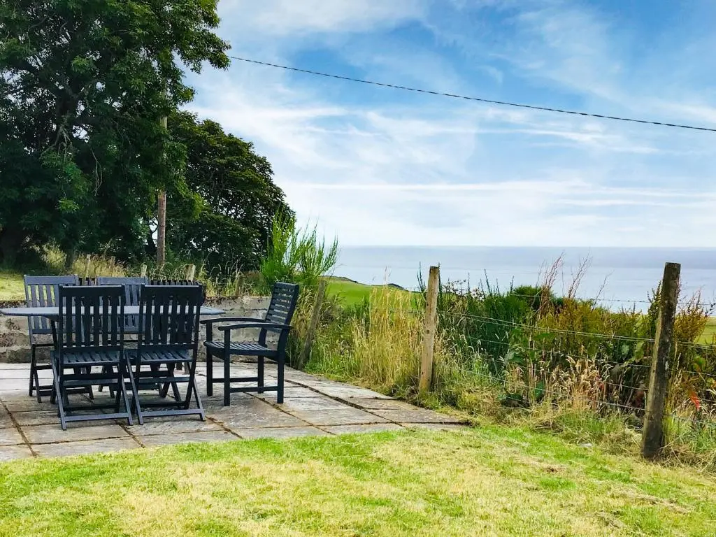 a table and chairs sitting on a patio overlooking the ocean at Owl Cottage in Kilmote