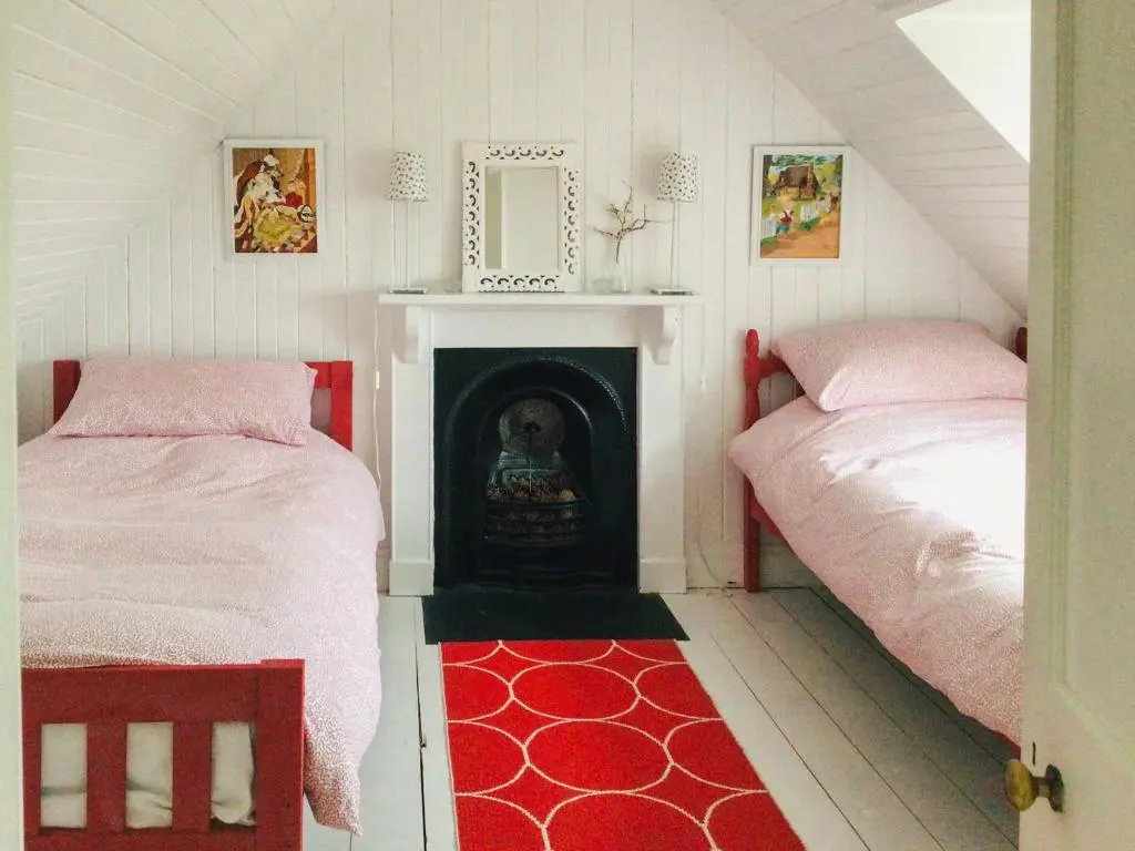 a room with two beds and a fireplace in a attic at Owl Cottage in Kilmote