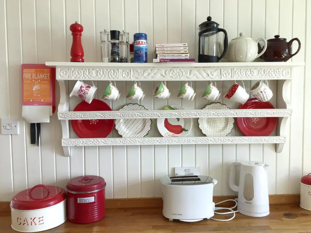 a kitchen with red and white dishes on shelves at Owl Cottage in Kilmote