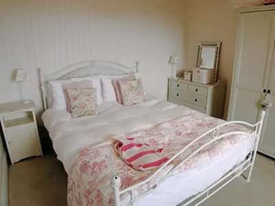 a bedroom with a white bed and a dresser at Owl Cottage in Kilmote