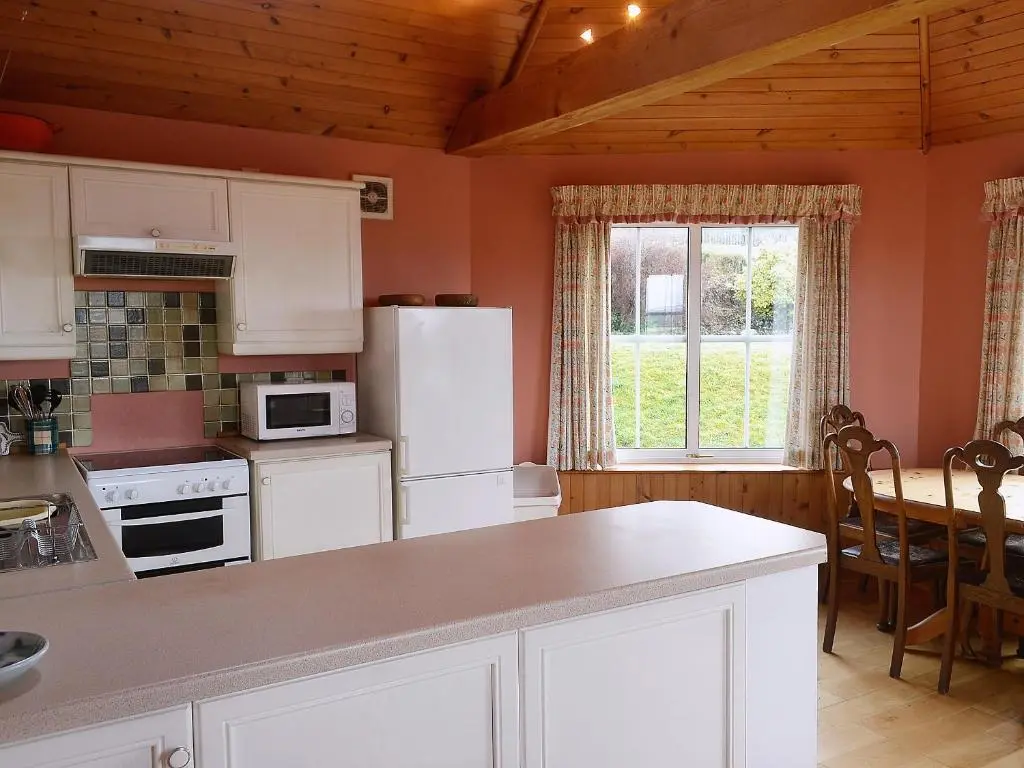 a kitchen with white cabinets and a table and a window at Rosscot in Ankerville