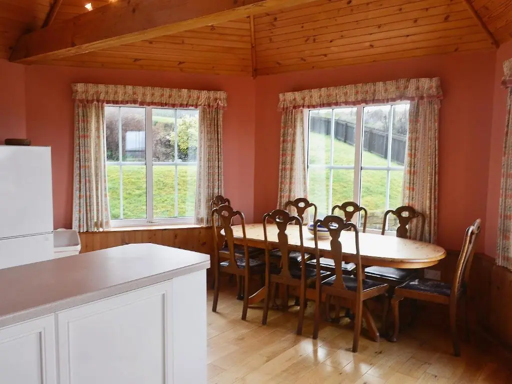 a dining room with a table and chairs and windows at Rosscot in Ankerville