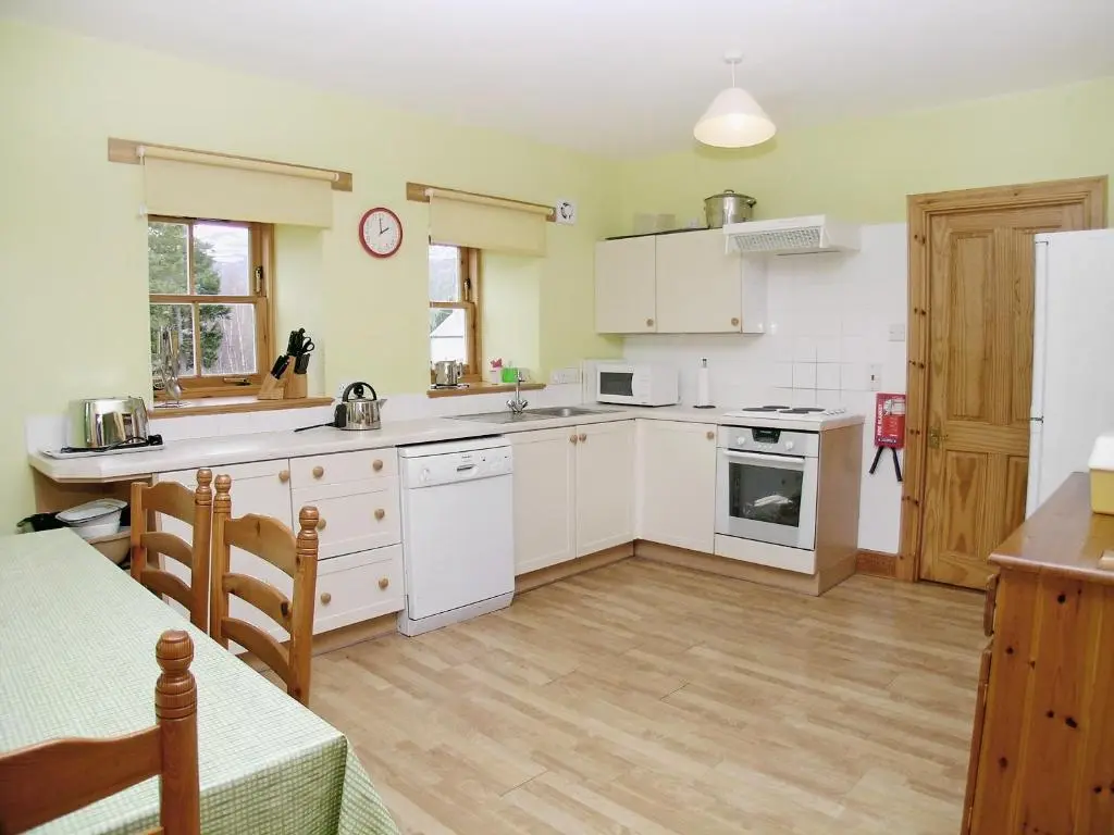 a kitchen with white cabinets and a white refrigerator at Mar House in Braemar