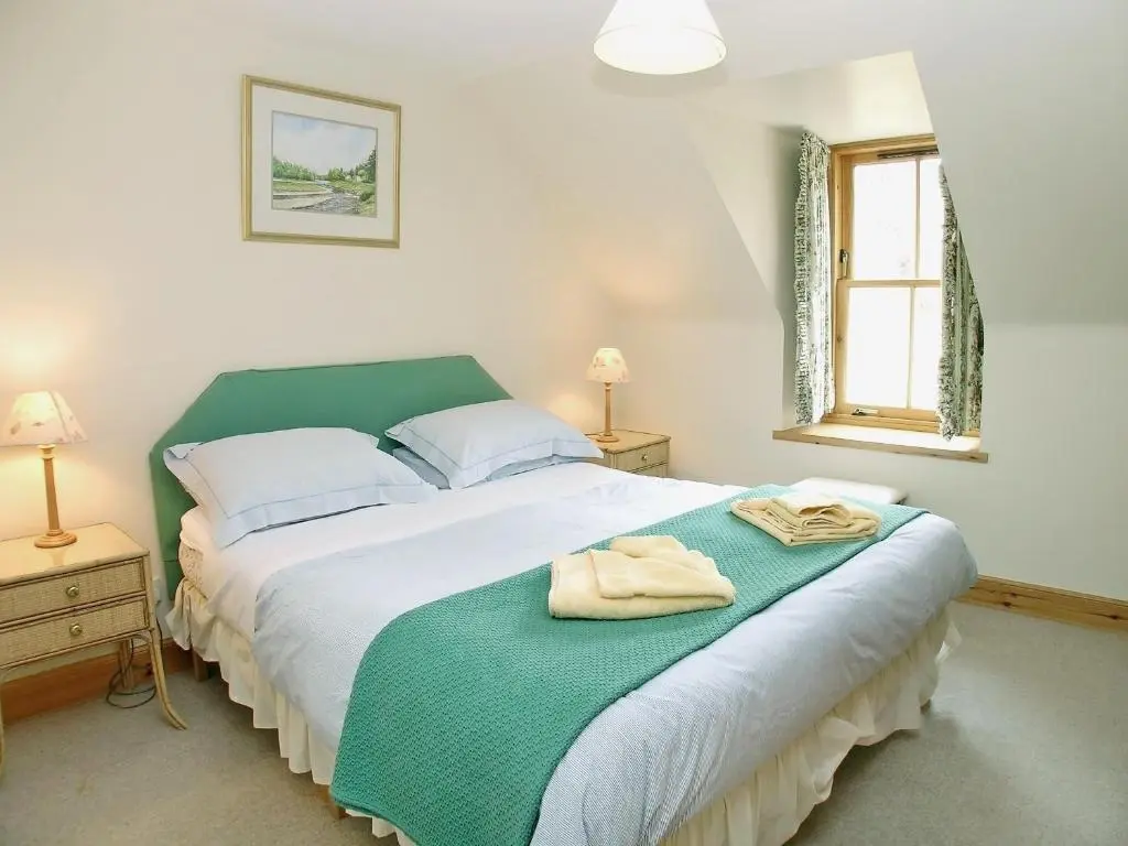 a bedroom with a bed with two towels on it at Mar House in Braemar