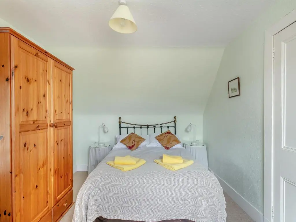 a bedroom with a bed with two yellow pillows at Meall Darroch in Inverey