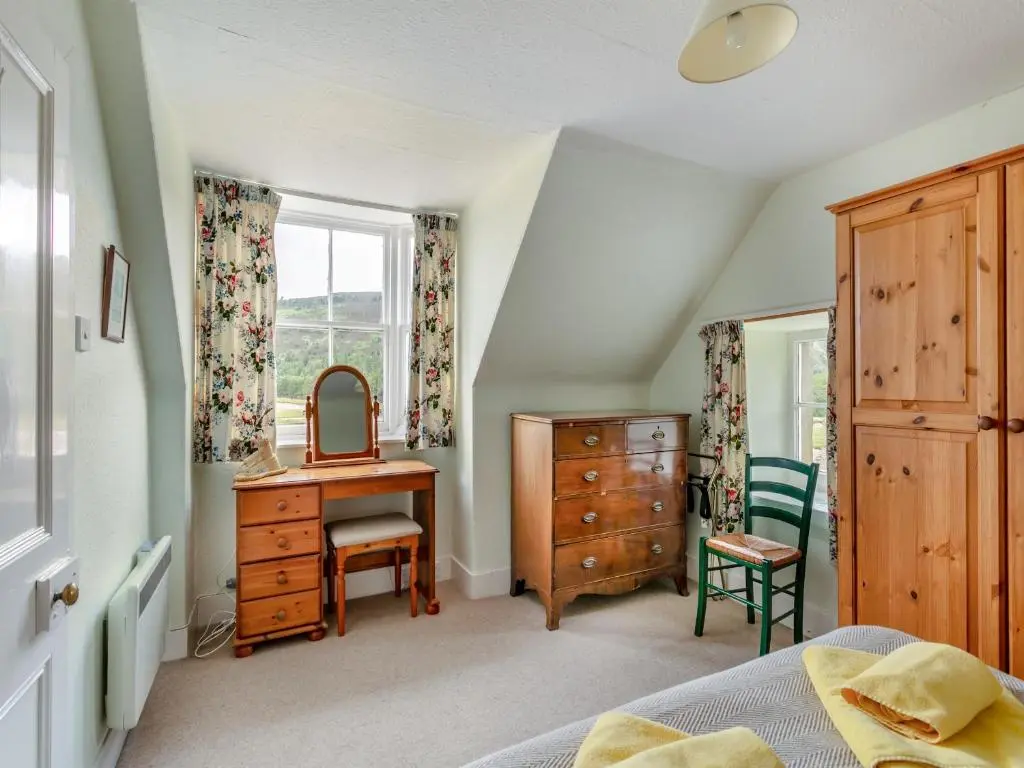 a bedroom with a dresser a desk and a mirror at Meall Darroch in Inverey