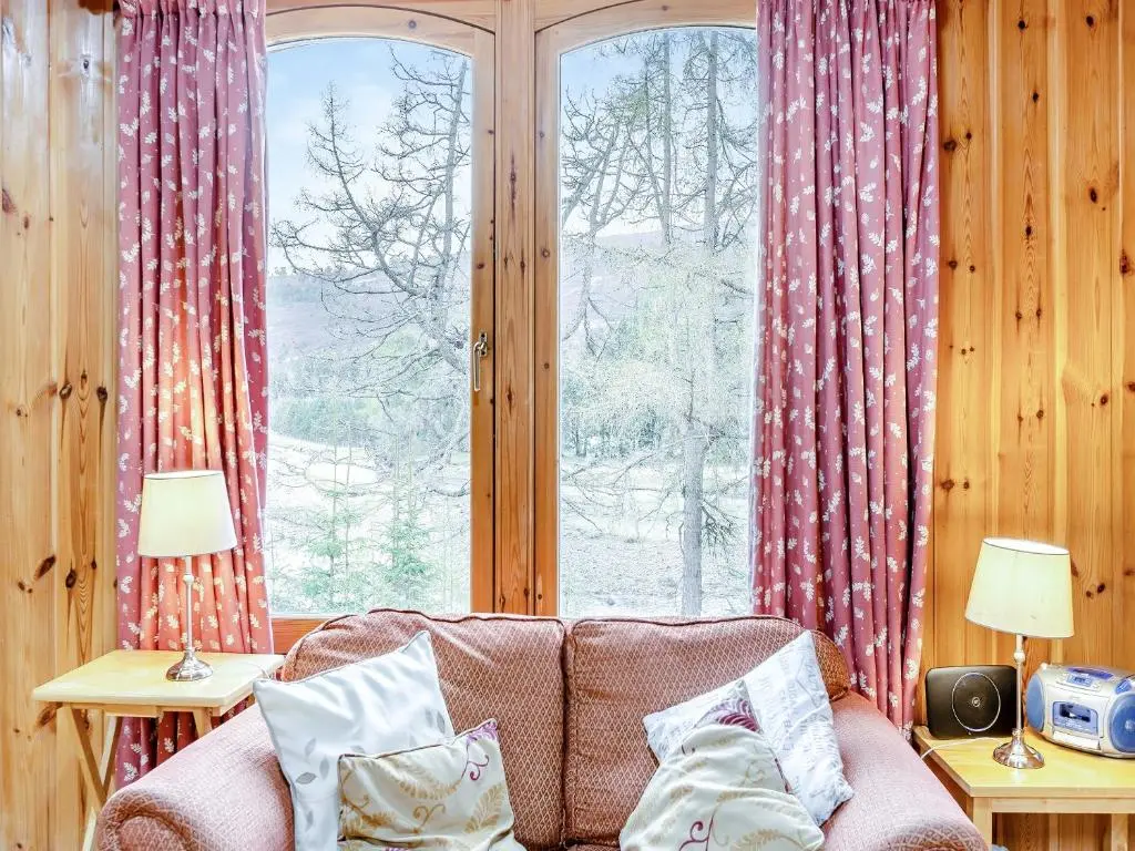 a living room with a couch in front of a window at Stuffer's Cottage in Inverey