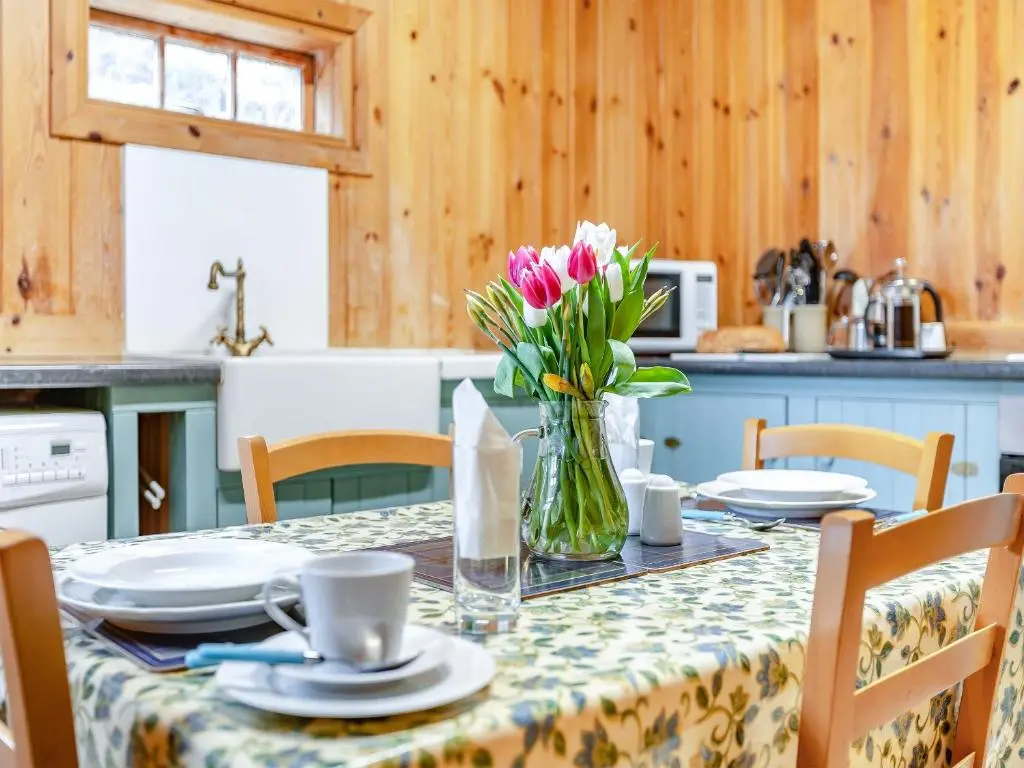 a table with a vase of flowers on it at Stuffer's Cottage in Inverey