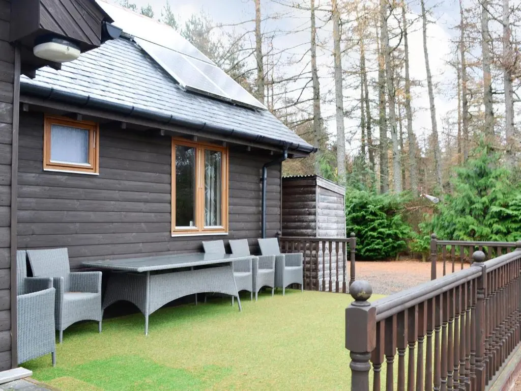 a patio with chairs and a table and a house at Park Lodge in Strachan