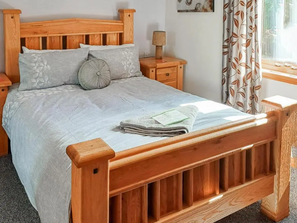 a wooden bed with a wooden frame in a bedroom at Park Lodge in Strachan