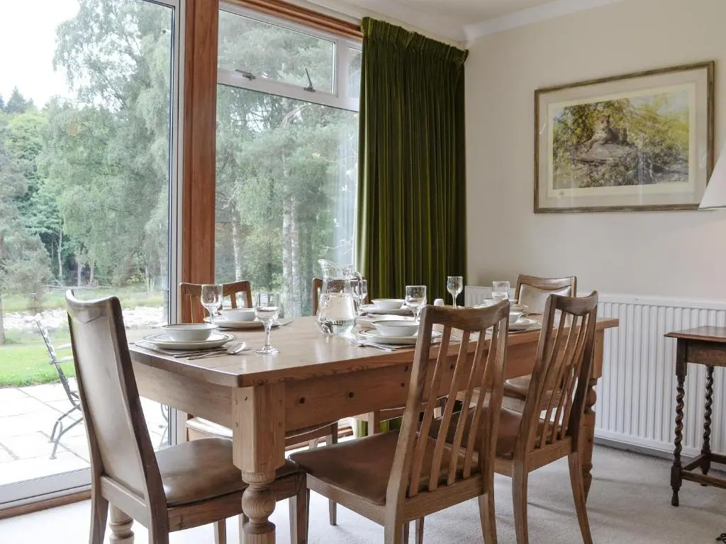 a dining room table with chairs and a large window at Laird's Cast in Banchory