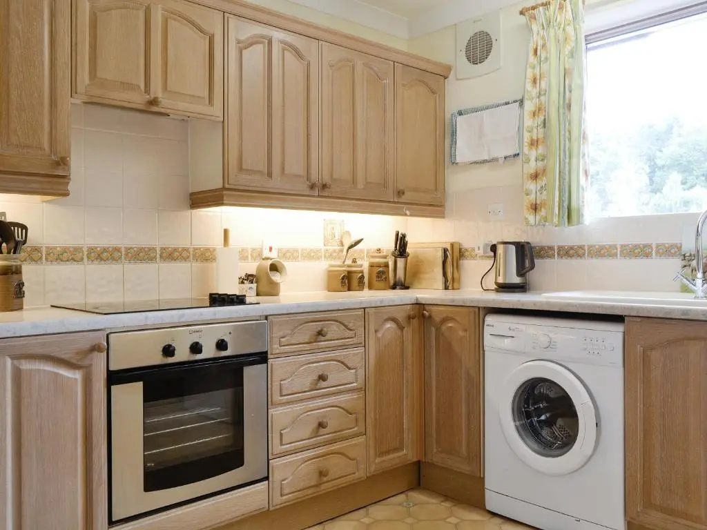 a kitchen with wooden cabinets and a washer and dryer at Laird's Cast in Banchory