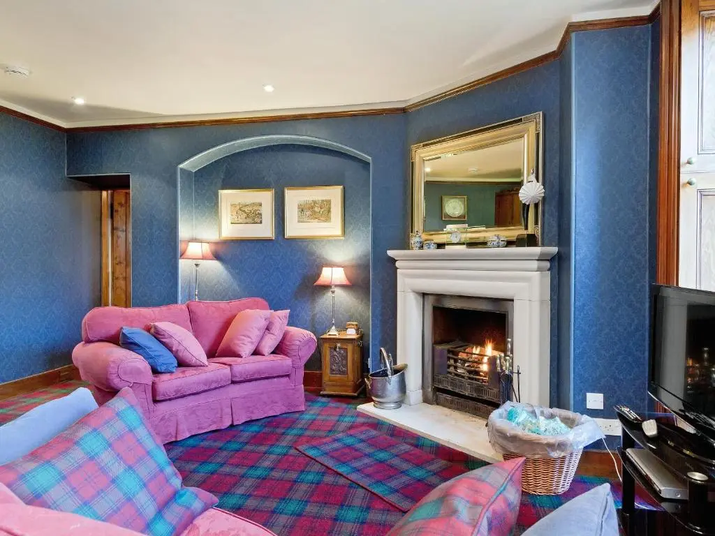 a living room with a pink couch and a fireplace at Dess Lodge in Kincardine O\u02bcNeil