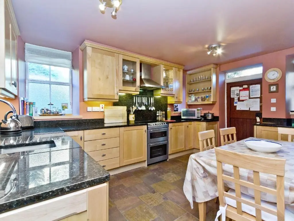 a large kitchen with wooden cabinets and a table at Dess Lodge in Kincardine O\u02bcNeil