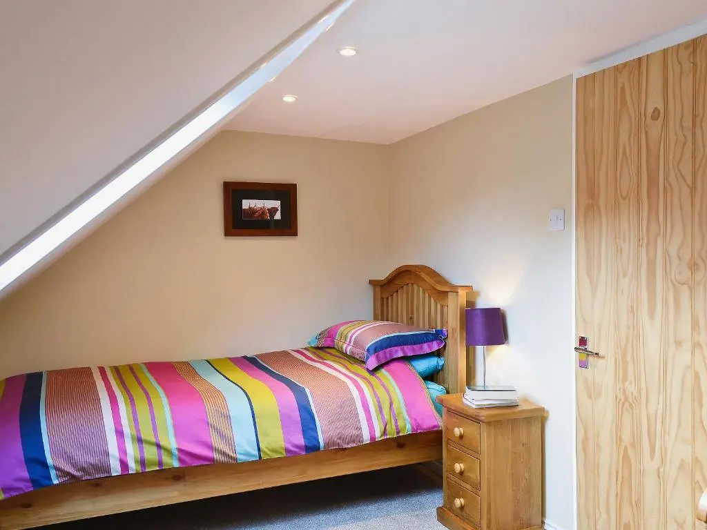 a bedroom with a bed with a striped blanket at Longcroft Cottage - 28233 in Old Rayne