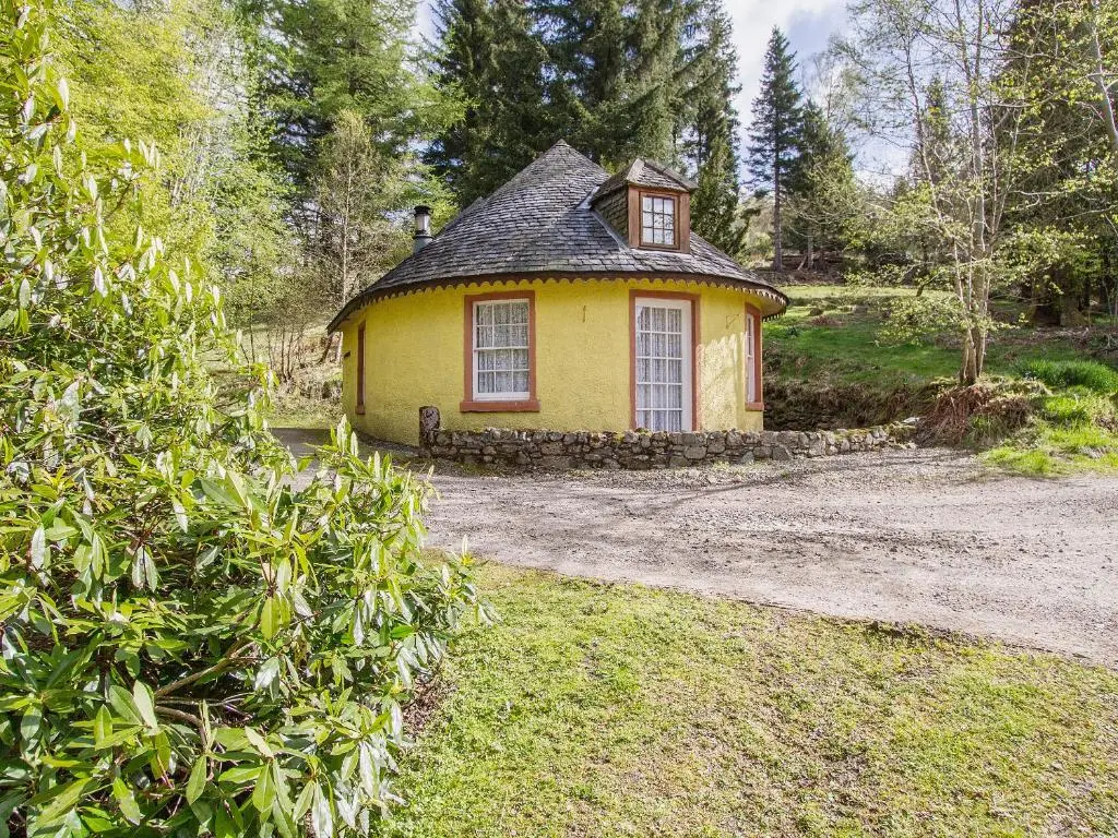 a small yellow house in the middle of a yard at Tinkerbell in Balnaboth