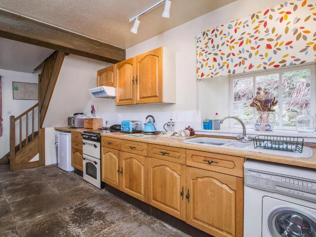 a kitchen with wooden cabinets and a sink and a window at Tinkerbell in Balnaboth