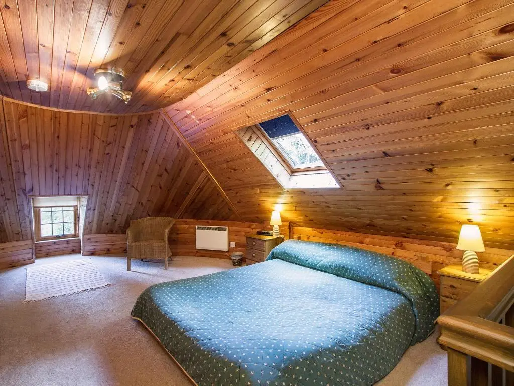 a bedroom with a bed in a wooden cabin at Tinkerbell in Balnaboth