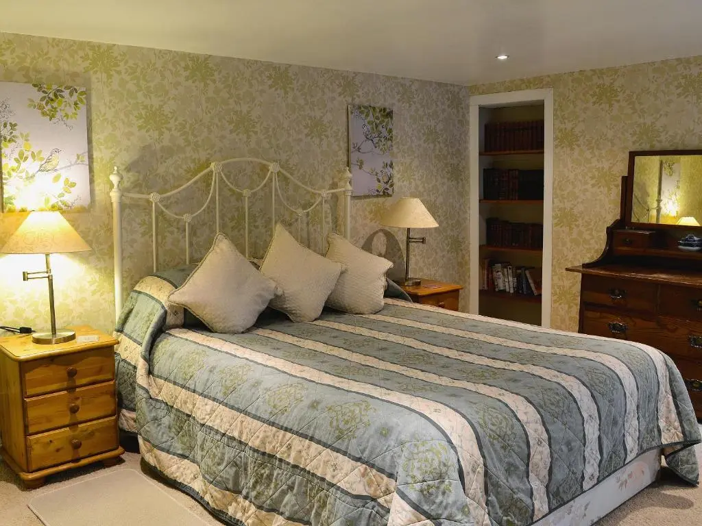 a bedroom with a bed and a dresser and lamps at Gardener's Bothy in Balnaboth