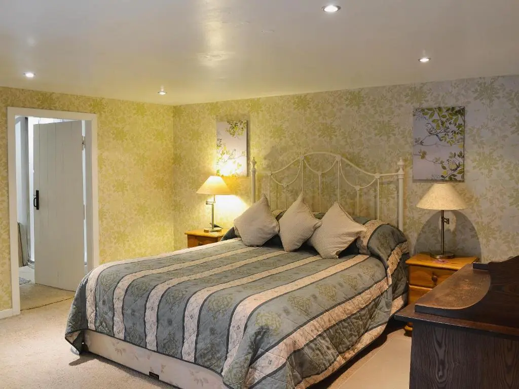 a bedroom with a large bed and two lamps at Gardener's Bothy in Balnaboth