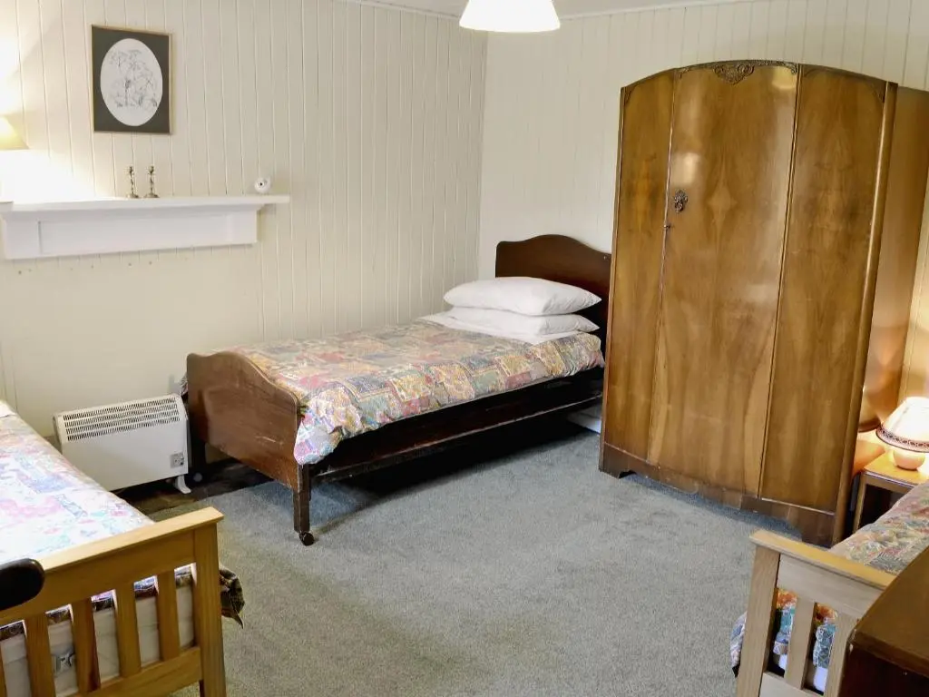 a bedroom with two beds and a wooden cabinet at Glentairre Cottage - Swww in Balnaboth