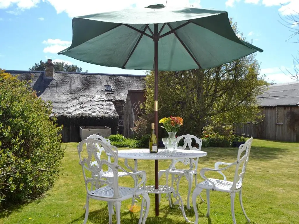 a table and chairs with an umbrella in a yard at Sunnyside in Kirkmichael