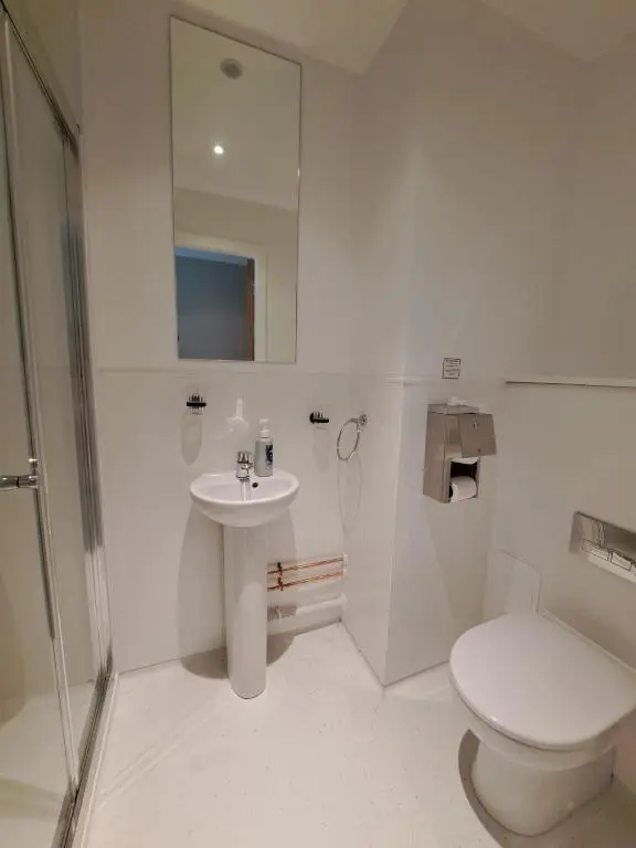 a white bathroom with a toilet and a sink at An Spiris Accommodation at Dundreggan Rewilding Centre in Dundreggan