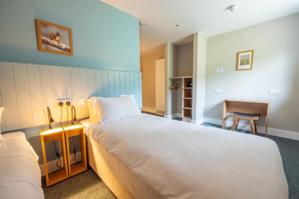 a bedroom with a large white bed and a desk at An Spiris Accommodation at Dundreggan Rewilding Centre in Dundreggan