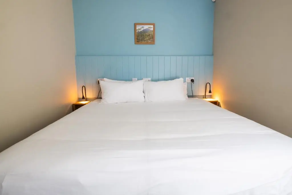 a large white bed in a room with two lamps at An Spiris Accommodation at Dundreggan Rewilding Centre in Dundreggan