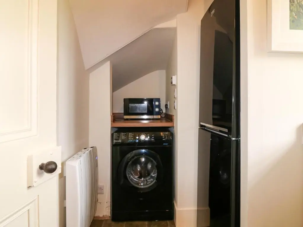 a washer and dryer in a hallway with a microwave at Holly Leaf Cottage - Drum Castle Estate in Banchory