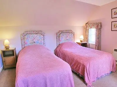 two beds in a bedroom with pink covers at Dhuallow in Aberarder