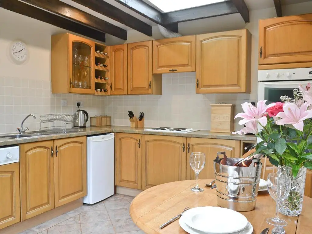 a kitchen with wooden cabinets and a table with flowers at Burns Cottage in Drumnadrochit