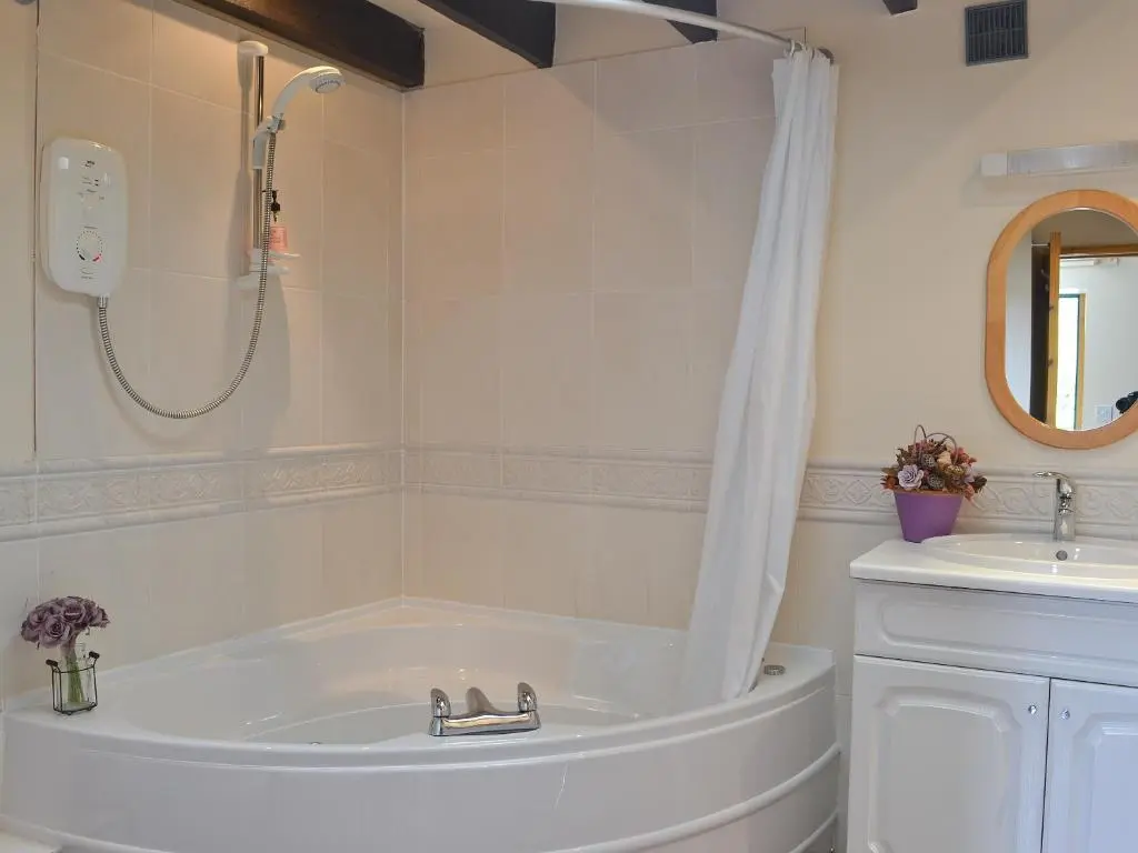 a bathroom with a tub and a shower and a sink at Burns Cottage in Drumnadrochit