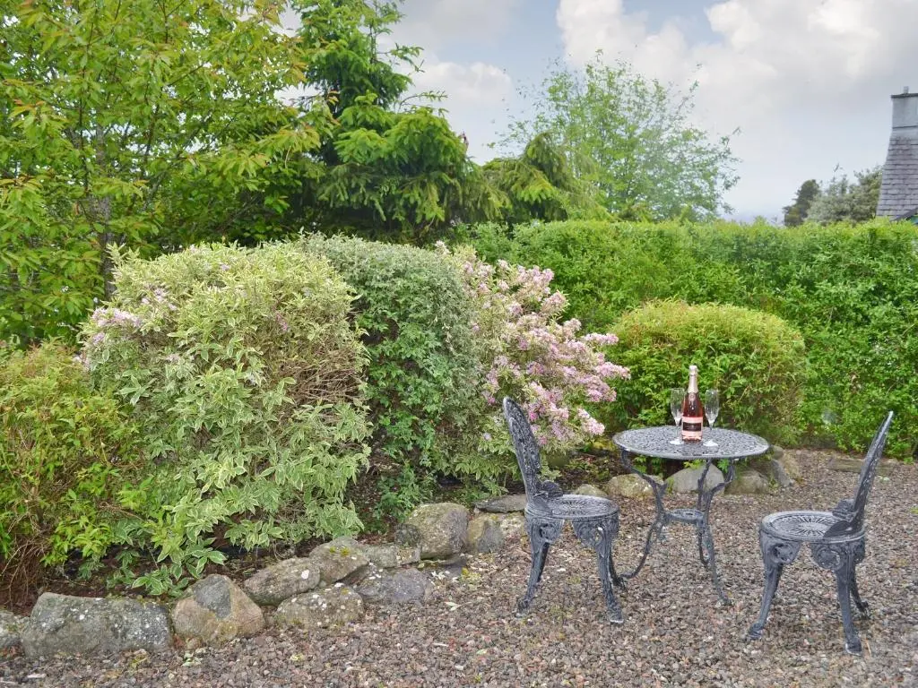two chairs and a table in a garden at Burns Cottage in Drumnadrochit