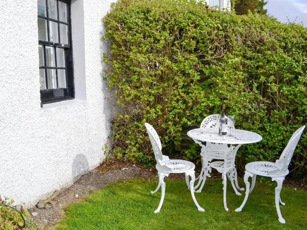 a table and two chairs sitting next to a bush at Temple House West in Drumnadrochit