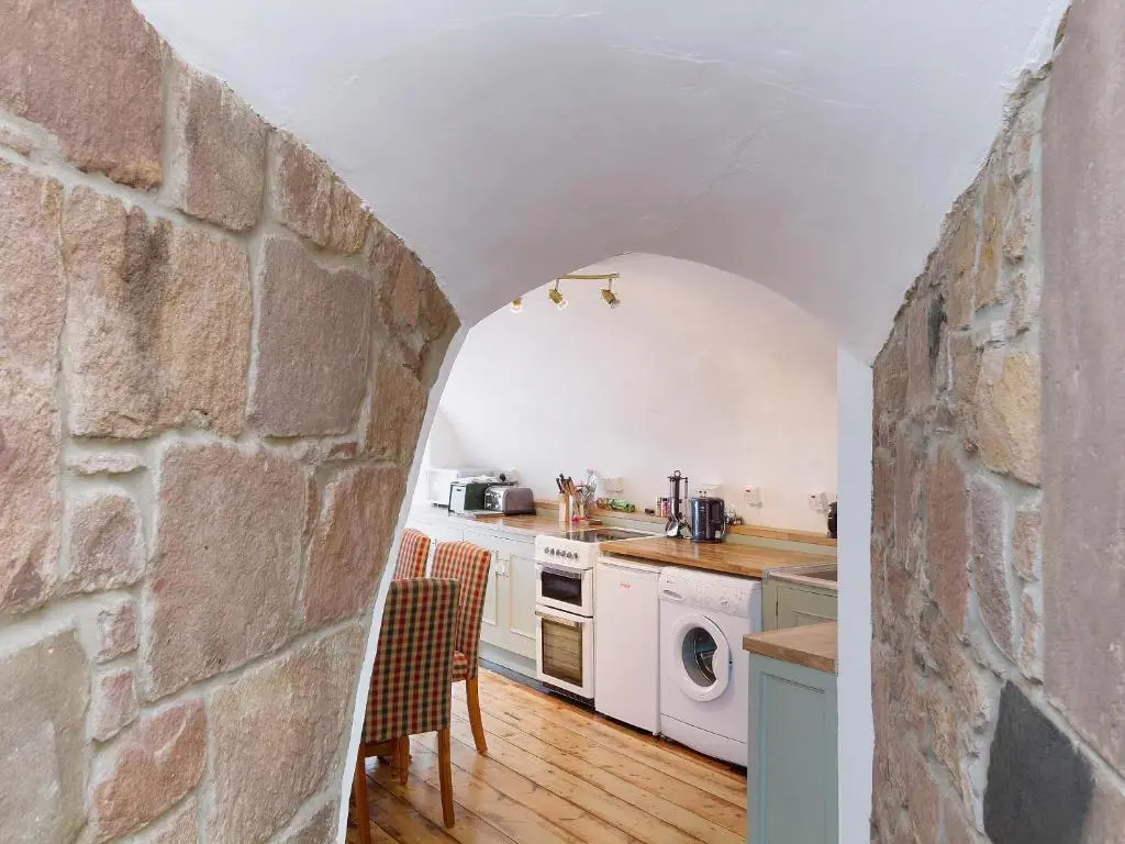 a kitchen with a stone wall and an archway at Symbister Suite in Turriff