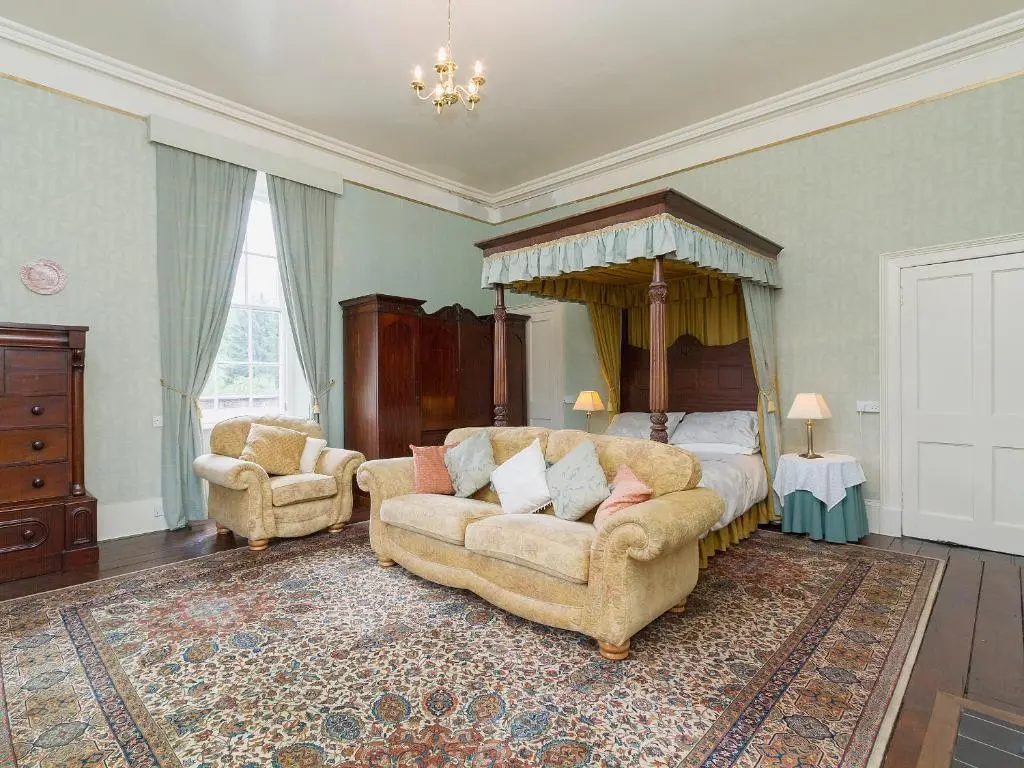 a bedroom with a bed and two chairs and a couch at Symbister Suite in Turriff